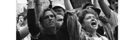 black and white image of people in a crowd protesting while holding hands in the air