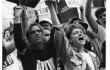 black and white image of people in a crowd protesting while holding hands in the air