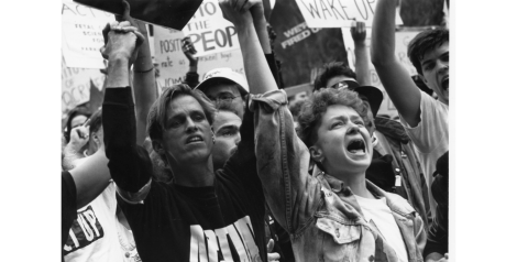 black and white image of people in a crowd protesting while holding hands in the air